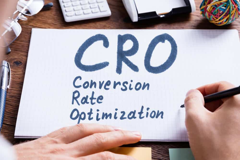 Close-up Of A Person's Hand Writing Conversion Rate - Infintech Designs