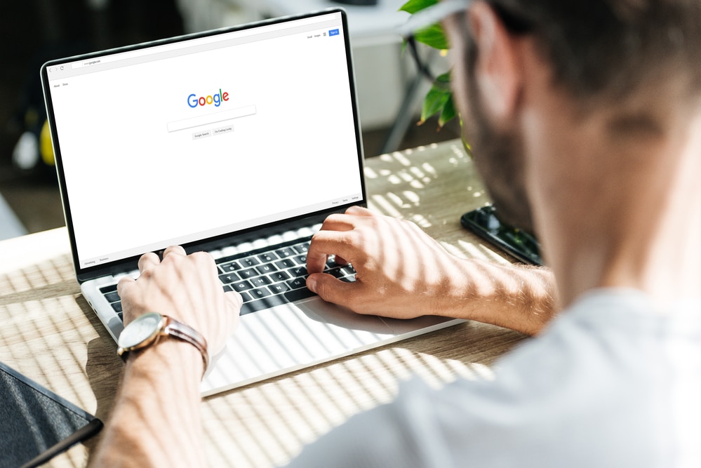 Cropped view of man using laptop with google website on screen - Infintech Designs